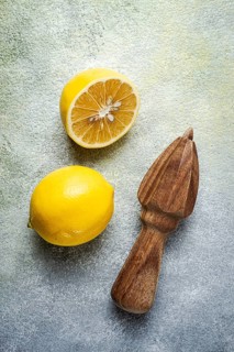 Wooden citrus reamer, manual lemon juicer, made of acacia wood, with citrus fruits on the table,
