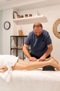 Professional masseur providing a therapeutic leg massage to a client in a spa or wellness center,
