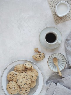 Table set for afternoon snack or breakfast with homemade cookies and coffee cup and milk jug. Top