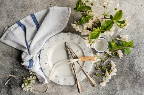 A beautifully arranged table setting features a plate, cutlery, and a thank you note tied with
