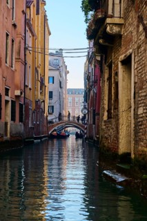 View from a gondola on a waterway in Venice going through the houses on a quiet and sunny morning