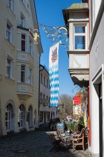 Picturesque old town alleyway with outdoor restaurants above a Bavarian state flag in the old town