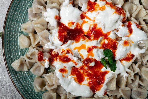 The dish features a generous serving of Turkish dumplings topped with velvety yogurt and a drizzle