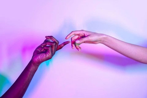A striking image of multiethnic hands reaching towards each other against a vibrant, colorful
