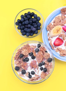 A vibrant breakfast setting featuring bowls of cereal with milk, topped with fresh blueberries,