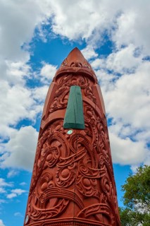 Artfully carved wooden structure with Maori patterns under a blue sky, New Zealand Maori Arts and