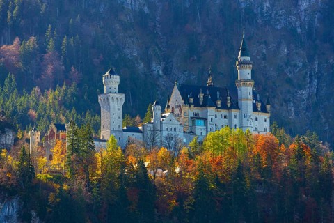 Fairytale castle in autumn, surrounded by colourful trees in an alpine landscape, Neuschwanstein
