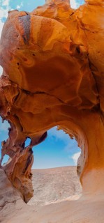 Captivating image of a natural rock arch showcasing vibrant, layered textures. The arch opens up to