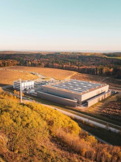 Aerial view of a factory next to woodland under a clear sky, Lindenrain industrial estate,