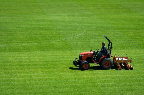 LUBIN, POLAND - MAY 4, 2023: Stadium Zaglebie Lubin. Man in tractor with multiple-purpose machine