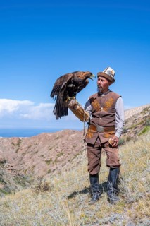 Traditional Kyrgyz eagle hunter with eagle in the mountains, near Kysyl-Suu, Kyrgyzstan