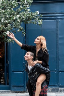Joyful lesbian couple share a playful moment. One partner carries the other on her back to reach