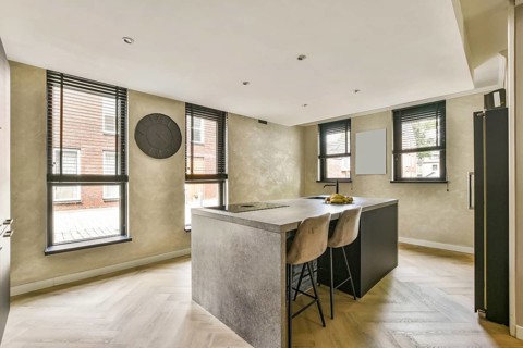 A stylish modern kitchen featuring sleek cabinetry, elegant bar stools, and ample natural light