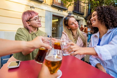 Group of diverse friends toasting with beer in an outdoor terrace at bar
