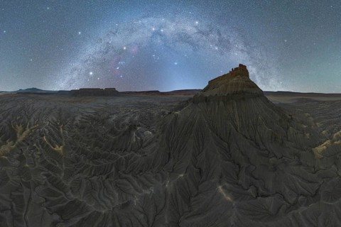A breathtaking milky way arches over the rugged sandstone formations in the Utah desert. The night