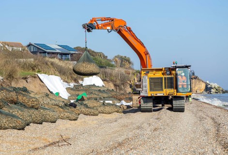 Emergency coastal defences work placing rock bags on beach to protect property, North Sea coast,