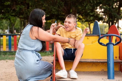 A loving mother and her son with cerebral palsy are enjoying a playful moment together at the park,
