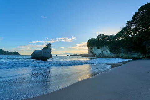 Beautiful beach scene at sunrise, with calm sea and large rocks on the coast, Cathedral Cove,