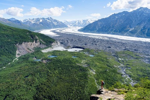 Young woman on a rocky outcrop enjoying the view, view of impressive mountain landscape with