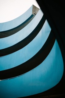 Architectural photograph of a blue parking lot building featuring multiple curved layers and a