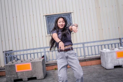 Asian young woman gesturing energetically dancing urban dance in the city