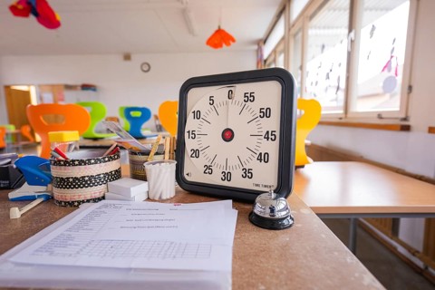 Clock and papers on an office desk in a modern room, bright windows, homework supervision,