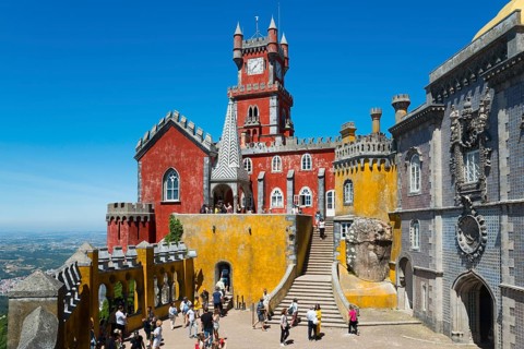 Colourful palace with red and yellow facades, many visitors and stairs, Palácio Nacional da Pena,