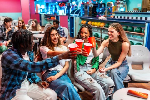 Group of cheerful young multiethnic friends toasting with red plastic cups while enjoying a fun