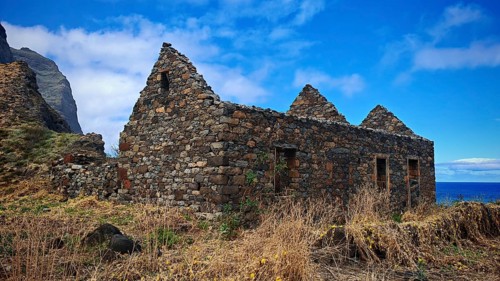 Abandoned stone houses, volcanic stone ruins nestled naturally in beautiful countryside with sea