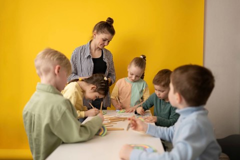 A group of children engaging in a creative art lesson, painting with brushes under the guidance of
