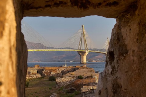 View through a window opening in a ruin of a large modern bridge across the Gulf of Corinth,