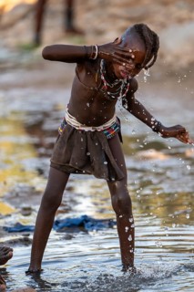 Himba child washing with water on a river, traditional Himba, Kaokoveld, Kunene, Namibia