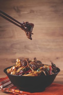 Udon noodles with beef in Mongolian style, with green onions and vegetables, served in a black