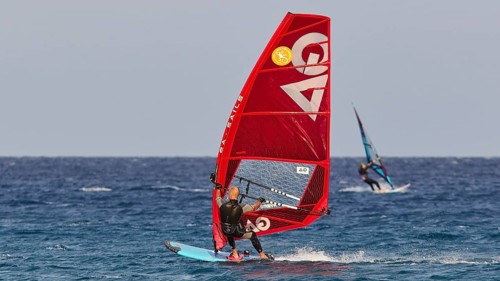A windsurfer with a red sail surfs over the blue sea, windsurfer, Meltemi windsurfing spot, Devils