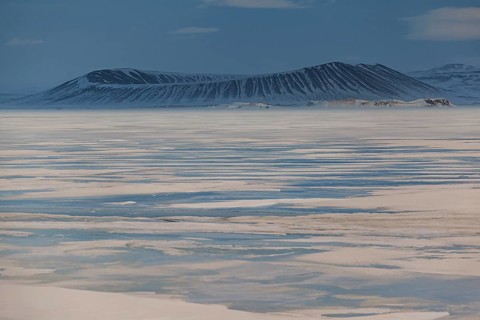 Frozen lake in a snowstorm, behind it Hverfjall crater, volcano, Myvatn, Iceland