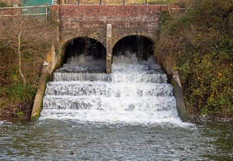 Bridge and weir with rushing water on River Marden, Bremhill, Calne, Wiltshire, England, UK