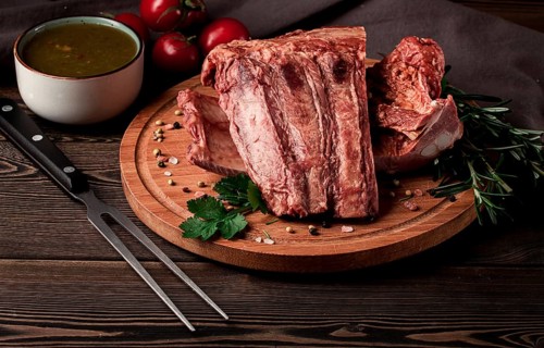 Smoked pork ribs, on a wooden table, top view, sauce, tomatoes and spices, close-up, vertical, no