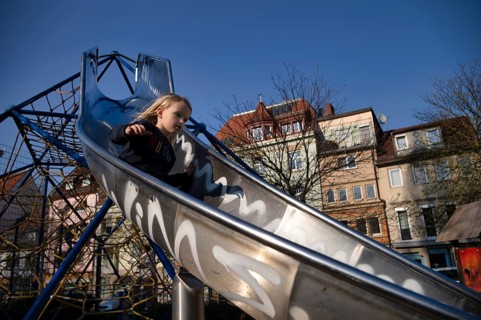 Girl, 4 years, blonde, sliding on slide, public playground, urban, Stuttgart, Baden-Württemberg,