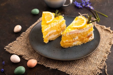 Lemon cake on black concrete background and linen textile, cup of coffee, side view, close up