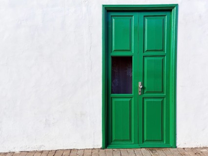 Typical green painted wooden door, white house wall, facade detail, text free space, Teguise,