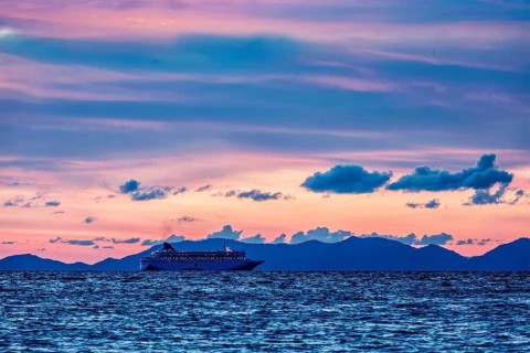 Vacation cruise background, sunset sea with cruise ship. Andaman sea, Thailand