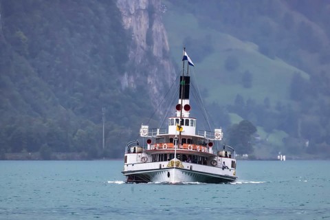 Historic paddle steamer URI travelling on Lake Uri. With the excursion boat to places of interest