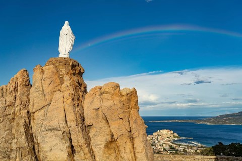 Rainbow on the statue of the Virgin Mary on a rock next to the Notre Dame de la Serra pilgrimage