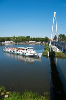 A ship sails under a modern bridge, with tourists on board, ship Talty, harbour and pier, Gizycko,