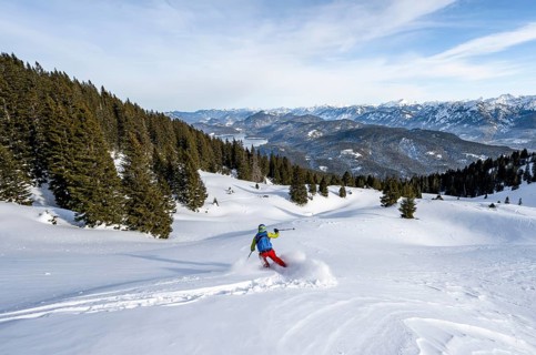 Skiers skiing down the Simetsberg, view of Walchensee and mountain panorama, Estergebirge, Bavarian