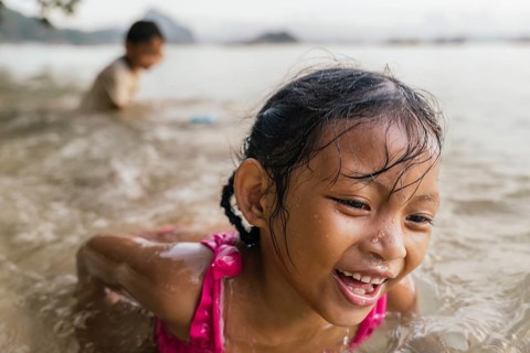 Two children are enjoying a playful day at the beach in the Philippines. One child, a girl, is in