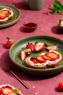 From above, a delightful brunch scene with fresh strawberries and cream cheese on toast, garnished
