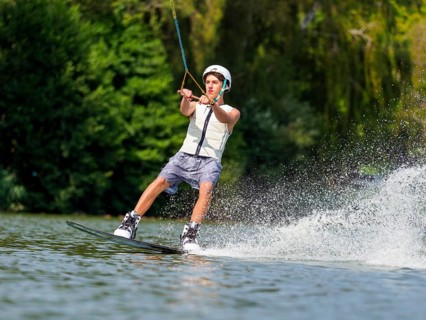 Young man with wakeboard in lake, water sports, water skiing in wakepark
