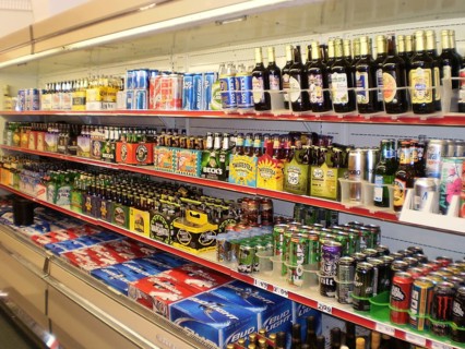 Shelf with a wide selection of colorful beer bottles and cans in a campground store shows how