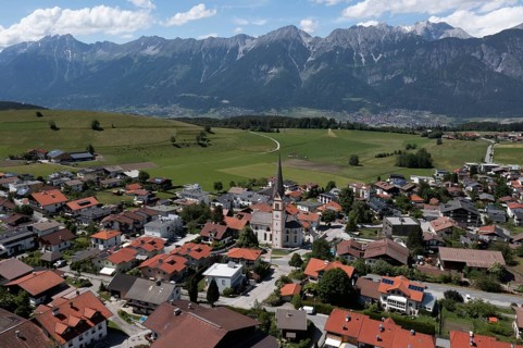Drone shot, view of village with parish church and Karwendel mountains, Rinn, Tyrol, Austria